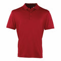 The PR615 by Premier is a plain red polo shirt featuring a classic collar and three buttons. Its short sleeves are neatly folded against a white background, accentuating the vibrant color and simple design.