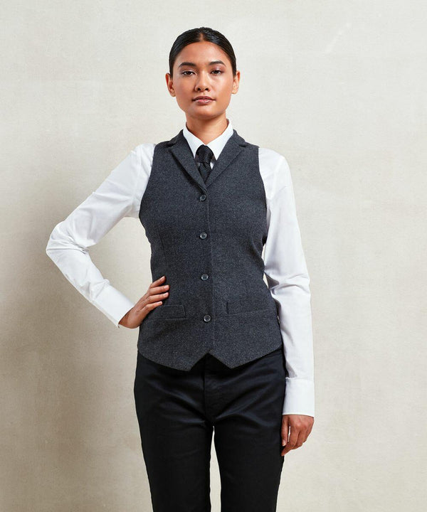 Person standing against a plain background, wearing a Premier PR626 white dress shirt, dark vest, dark pants, and a tie.