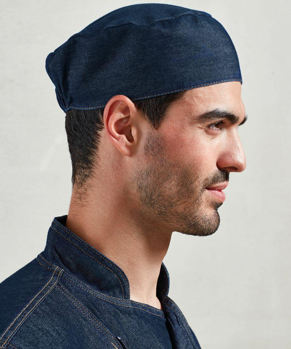 A man in profile wearing a Premier PR653 dark blue denim cap and matching jacket, standing against a plain light gray background.