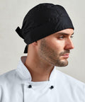 A person wearing a black chef's hat and a white double-breasted Premier PR658 jacket looks to the right.