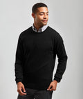 A person wearing a black Premier PR692 sweater over a light gray collared shirt, standing against a plain background.