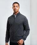 A man stands against a plain light background, wearing a Premier PR695 over a light blue collared shirt.