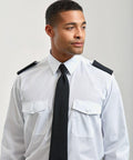 An individual wearing a white dress shirt with black epaulettes and a black tie, looking off to the side against a plain background, is showcasing the Premier PR700.