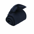 A neatly rolled PR710 dark blue tie by Premier placed on a white background.