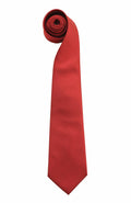 A vibrant red PR765 necktie by Premier, featuring a smooth texture and classic design, is elegantly coiled at the top. It rests on a plain white background, accentuating its vivid color and rolled-up appearance.