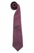 A Premier PR765 necktie in dark purple, featuring a smooth texture, is elegantly arranged in an elongated S-shape against a plain white background.
