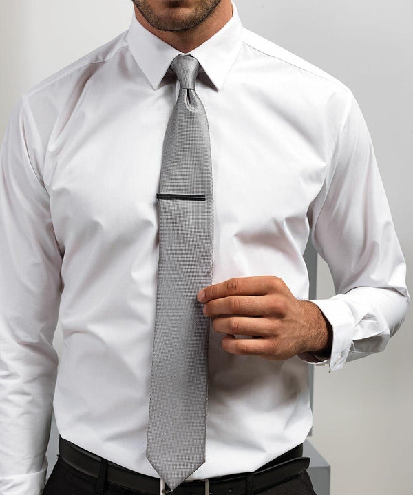 A man in a white dress shirt and gray tie adjusts his Premier PR780.
