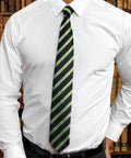 A person wearing a white Premier PR783 dress shirt and a black tie with green diagonal stripes, standing in front of a bookshelf.