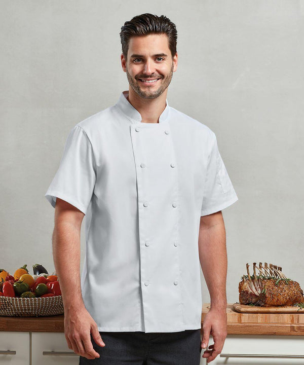 A man in a white chef's coat stands in a kitchen with a countertop in the background. On the countertop sits a Premier PR902 alongside assorted vegetables in a basket and a rack of cooked meat.