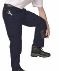 A person in PW101 work pants by Portwest with knee pads and black boots adjusts a tool in a side pocket.