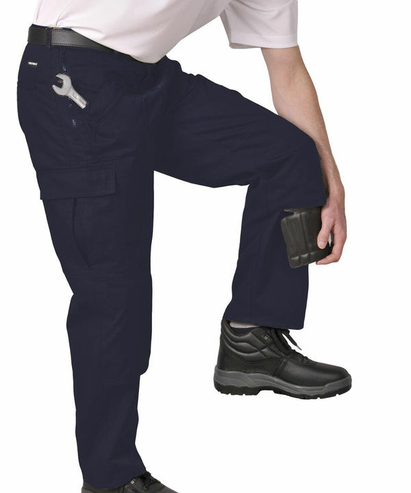 A person in PW101 work pants by Portwest with knee pads and black boots adjusts a tool in a side pocket.