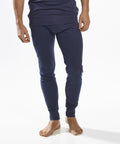 A person wearing navy blue Portwest PW142 thermal underwear stands barefoot against a white background. The image focuses on the lower body, showing the thermal pants.