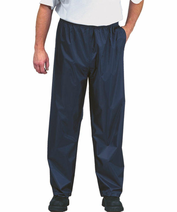 Person wearing a white shirt and dark-colored waterproof Portwest PW167 pants with hands in pockets, standing on a white background.