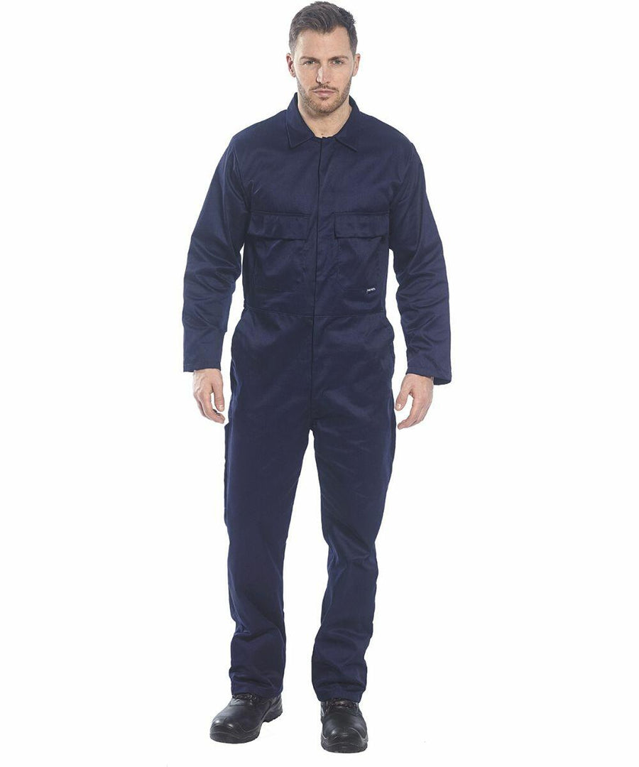 A man stands facing forward, wearing a navy blue PW200 coverall from Portwest and black shoes.
