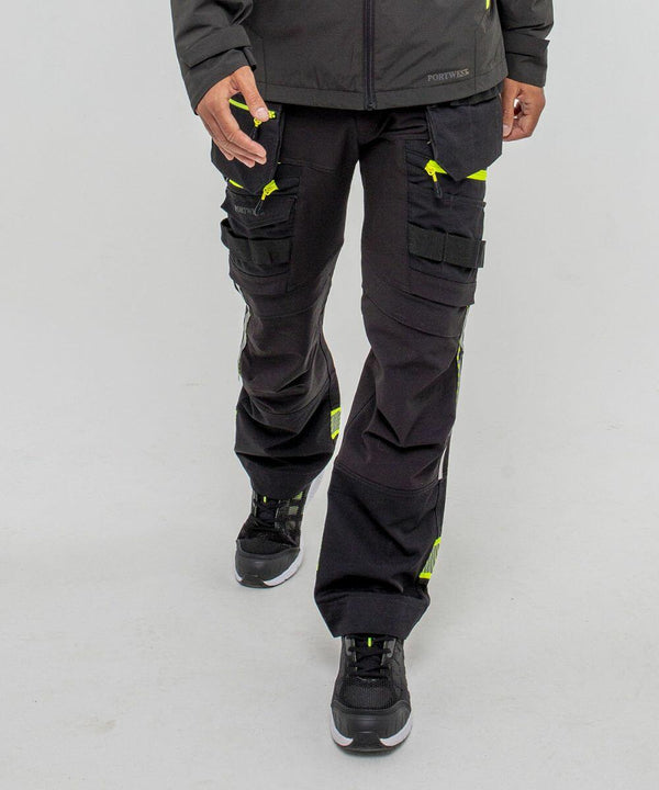 A person wearing black cargo pants with yellow accents and black PW260 sneakers by Portwest is standing against a plain white background.