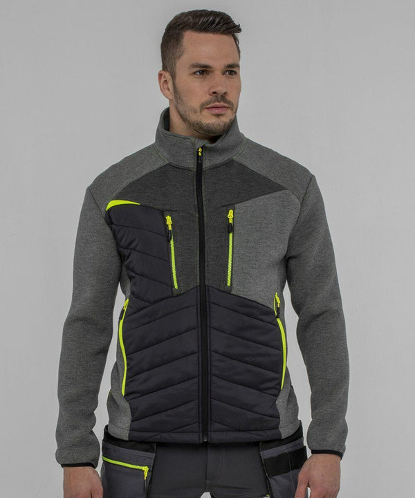 A man wearing a Portwest PW262 jacket with neon yellow zipper accents and black quilted panels stands in front of a plain grey background.