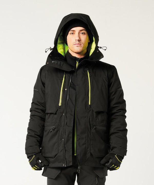 A person stands facing forward wearing the Portwest EV4 Winter Parka Jacket (EV461) with neon yellow-green lining and details, paired with black gloves and a black beanie. The background is plain white.