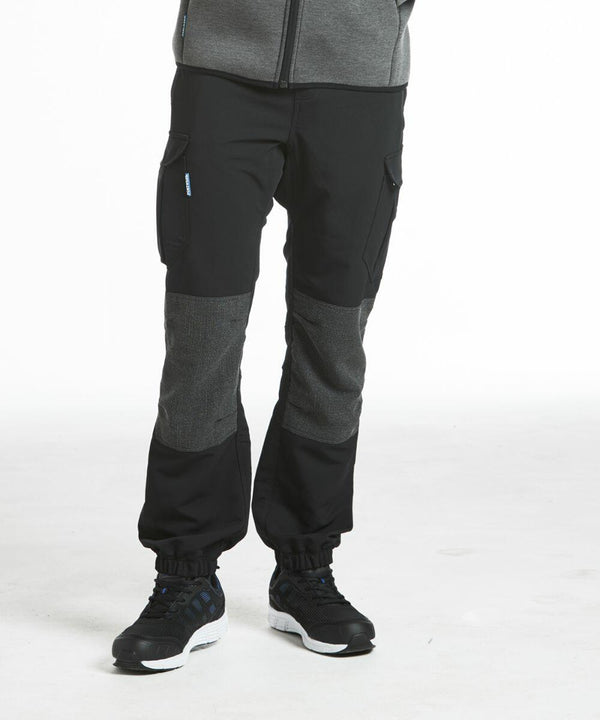 Person wearing black and gray athletic pants with pockets (PW291 from Portwest) and black athletic shoes, standing against a plain white background.
