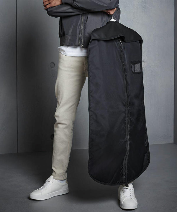 Person in beige pants, white sneakers, and a gray jacket holding a Quadra QD031.