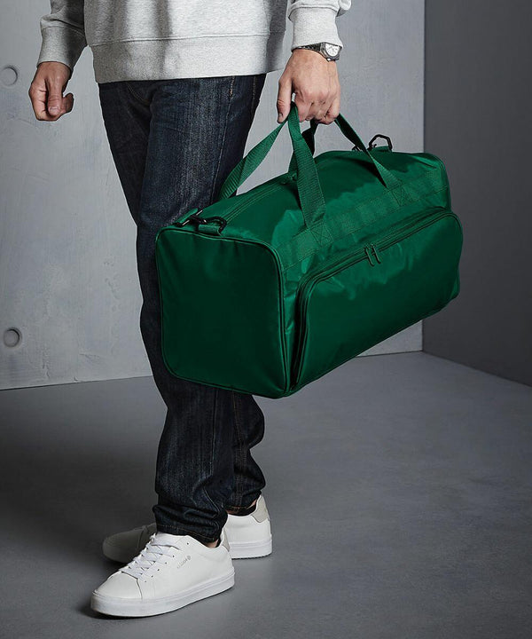 A person in casual attire stands holding a Quadra QD045 in their right hand, with part of their torso and legs visible.
