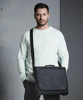 A man with short dark hair, wearing a light mint green sweatshirt and black pants, is holding a Quadra QD090 standing in front of a gray background.
