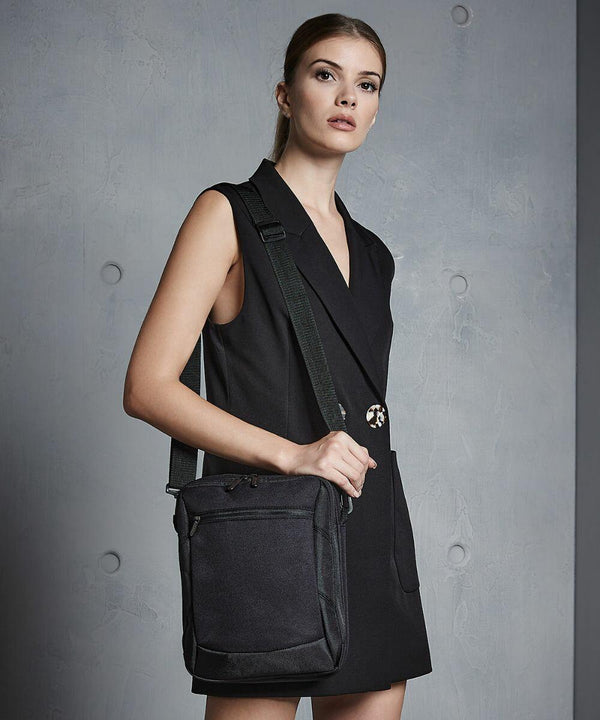 A woman in a black sleeveless blazer dress stands against a gray backdrop, holding a Quadra QD264.