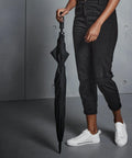 Person dressed in black pants and white sneakers holding a closed black Quadra QD360.