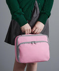 Person holding a pink Quadra QD435 with gray trim, dressed in a green sweater and gray skirt, standing against a plain background.