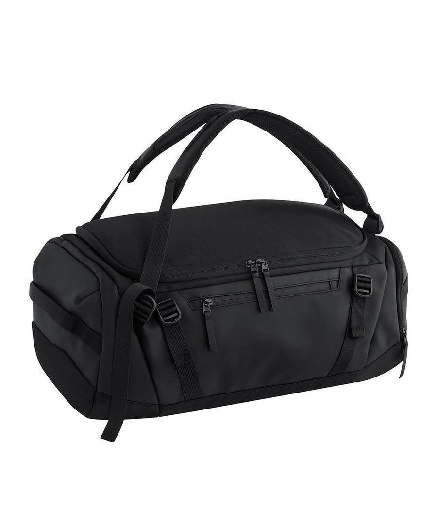 A sleek, minimalist black Bags duffel with two top handles, zippered compartments, and adjustable straps is displayed on a white background.