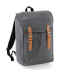 Introducing the Quadra QD615: a stylish gray canvas backpack featuring elegant brown leather buckle straps on the front and a convenient flap closure. The straps are adorned with silver buckles, complemented by adjustable black shoulder straps for comfortable carrying.