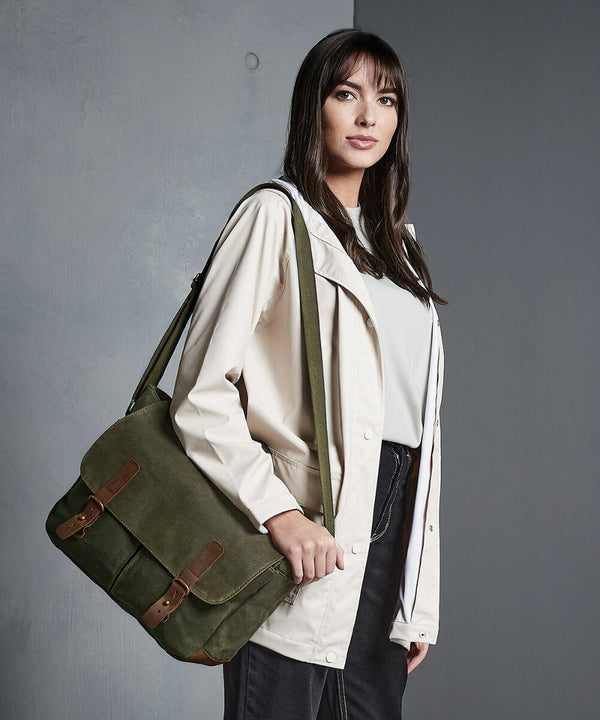 A person wearing a cream jacket and black pants, carrying a Quadra QD653, stands against a grey background.