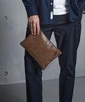 A person in dark pants and a blue shirt holds a Quadra QD889 against a gray background.