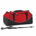 The QS070 by Quadra is a red and black duffle bag featuring multiple compartments and black straps. This bag includes a main zippered section, smaller side pockets, and an adjustable shoulder strap alongside it.