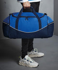 Person holding a large blue and black Quadra QS070 while wearing black pants and white athletic shoes.