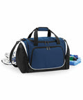A blue and black Quadra QS277 duffel bag with black straps, surrounded by a pair of white athletic shoes, a rolled blue towel, and small toiletry bottles.