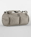 A light gray QS320 from Quadra with two front zippered pockets, shoulder straps, and handles. The QS320 has a cylindrical shape and a minimalist design.