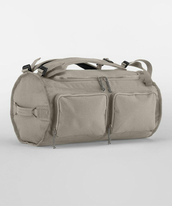 A light gray QS320 from Quadra with two front zippered pockets, shoulder straps, and handles. The QS320 has a cylindrical shape and a minimalist design.