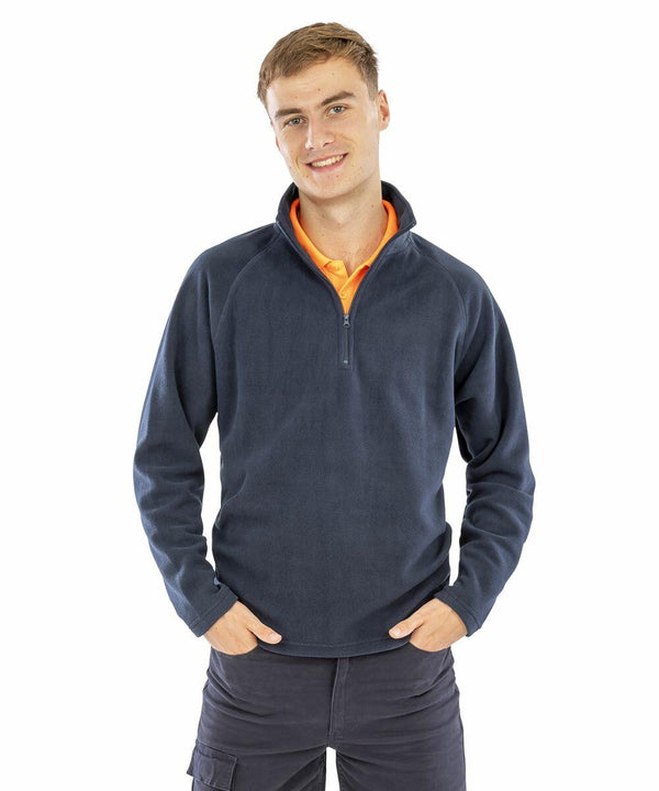 A person wearing a dark blue long-sleeve Result R112X zip-up sweater and dark pants stands with hands in their pockets, smiling at the camera.