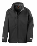 The Result R121J is a black softshell jacket featuring a high collar, full zipper, chest pocket, and a smooth, weather-resistant exterior.