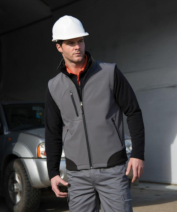 A man wearing a hard hat, gray vest, and dark shirt stands next to a parked Result R123A.