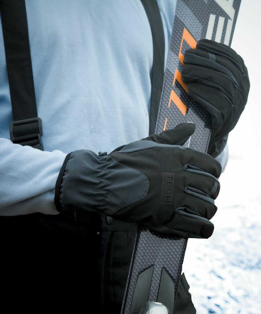 A person wearing black gloves and a blue long-sleeve shirt holds a pair of Result R134X skis upright against their body.