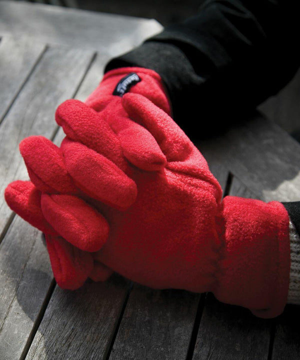 A person wearing Result R144X fleece gloves clasps their hands together on a wooden surface.