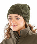 A person with curly hair wearing a green Result R159X beanie and a zipped-up brown jacket, looking slightly to the side and smiling.