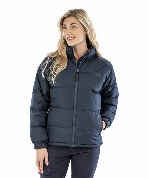 A woman with long blonde hair wearing a dark Result R181F puffer jacket and dark pants, standing against a white background.