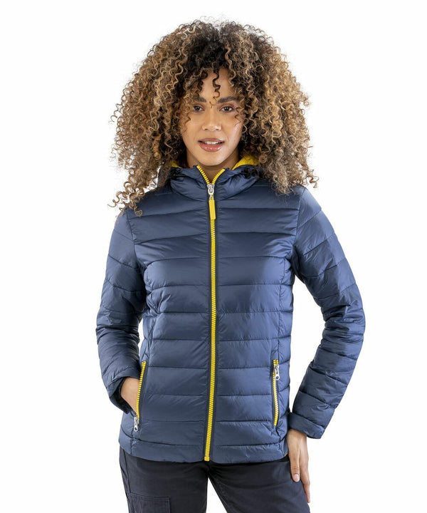 A person with curly hair wears a blue puffer jacket with yellow zippers, standing with hands in pockets, which is the R194F from Result.
