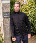 A man in a Result R209X jacket stands outdoors next to a wooden post with a sign reading "Middle House.