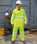 A person wearing a white hard hat and neon yellow safety gear stands in front of a portable oxygen tank and coil of hoses. The background includes metal equipment and a shipping container, while the individual is equipped with Result's R216X.