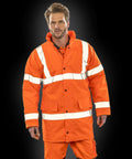 A person wearing a Result R218X orange reflective safety jacket and matching pants stands against a black background.