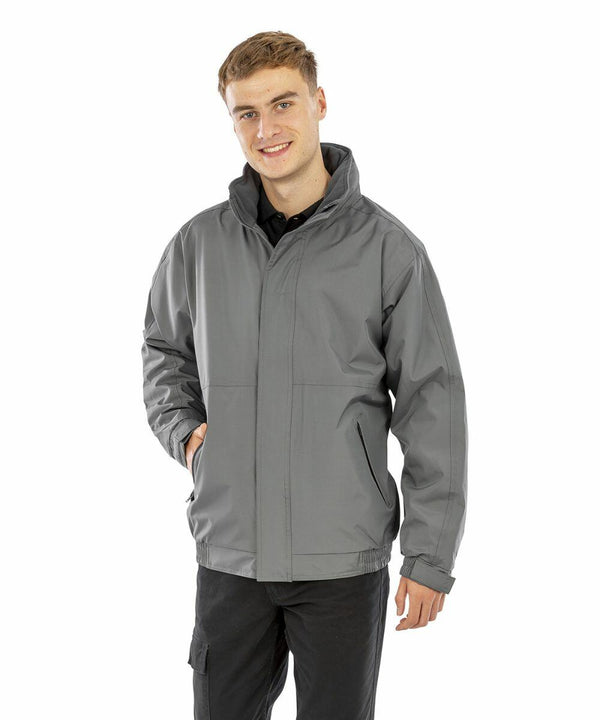 A person wearing a grey Result R221M with one hand in the pocket, smiling at the camera against a white background.