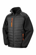 Introducing the R237X jacket from Result Genuine Recycled, which boasts a striking combination of a quilted body in black and dark gray paired with softshell sleeves. This stylish piece is enhanced by bright orange zippers on the pockets and front, along with a high collar and elastic cuffs for added comfort.